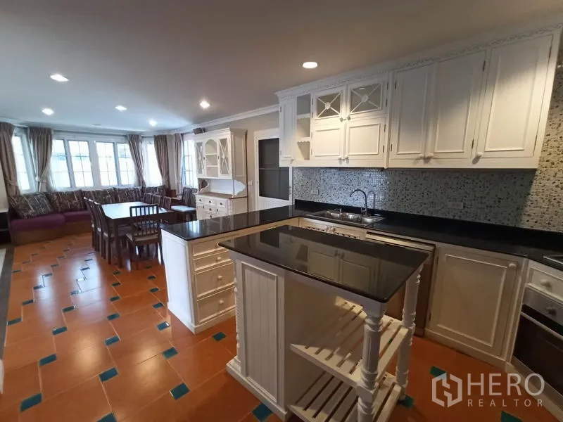 Detached House for rent in Mueang Samut Prakan, Samut Prakan - Fully fitted kitchen with white cabinetry, black granite countertops, island and mosaic backsplash.