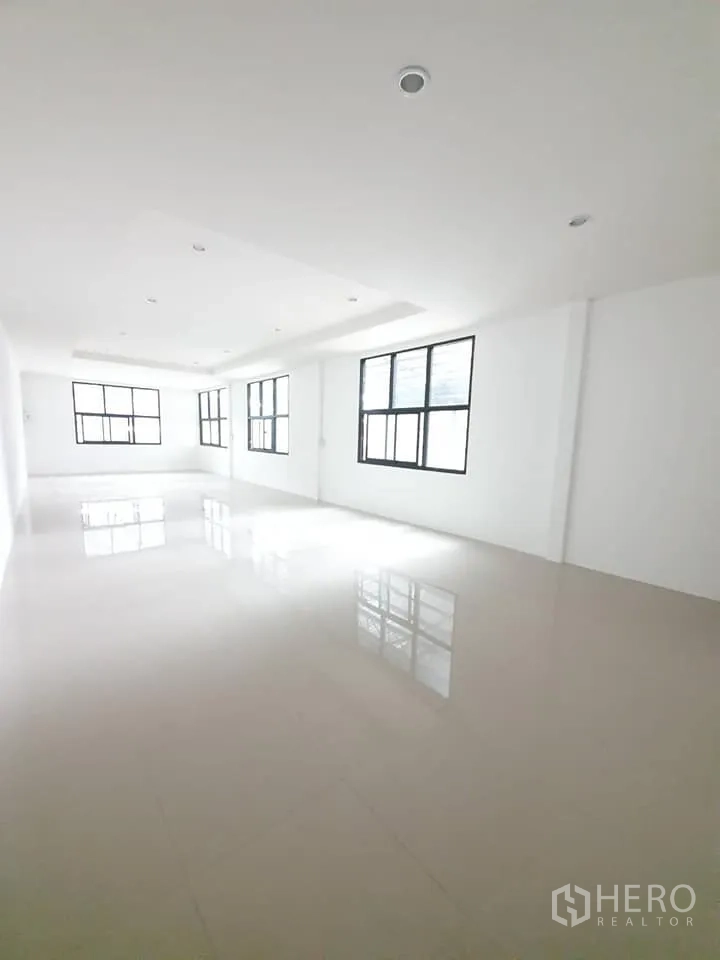 Warehouse for rent in Bang Khen, Bangkok - Bright tiled office room inside the warehouse with recessed lighting and large windows.