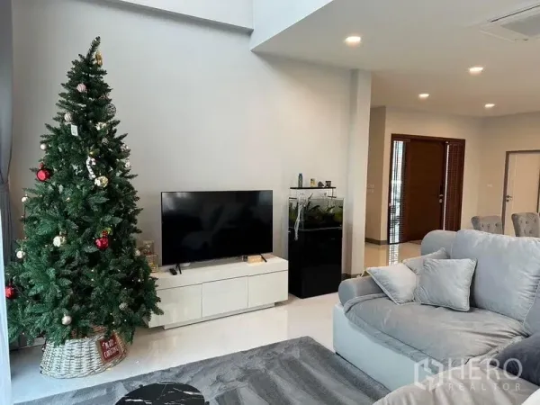 Detached House for rent in Bang Phli, Samut Prakan - Living area with TV cabinet, aquarium, soft sectional sofa and doorway to dining space.