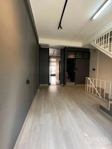 Home Office for rent in Khlong Toei, Bangkok - Open room with light wood flooring facing a glass door and internal stairs.