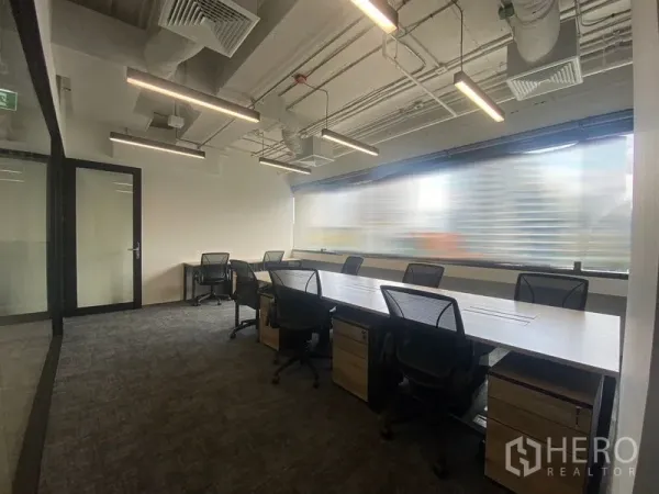 Office Space for rent in Bang Rak, Bangkok - Window-lined office with bench desks, mesh chairs and linear LED lighting.