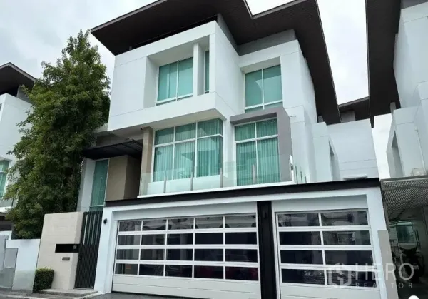 Detached House for sale in Suan Luang, Bangkok - Modern three-storey detached house facade with wide glass garage door and large windows in Bangkok.