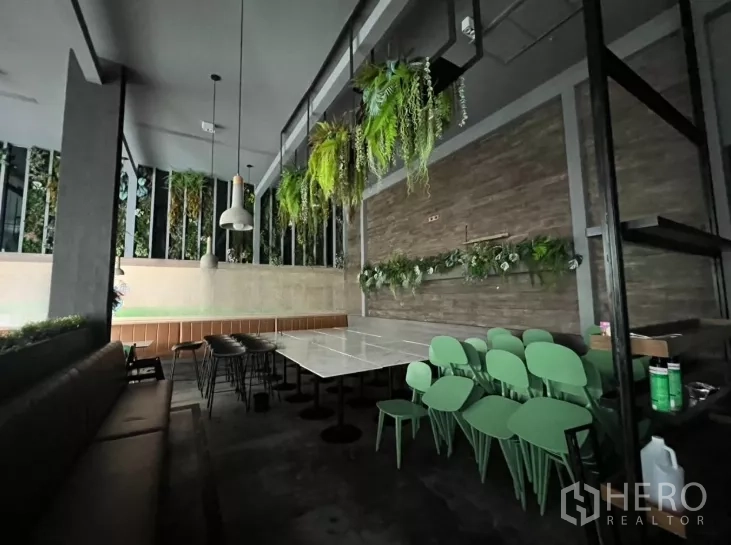 Retail Space for rent - Corner dining section with marble tables, green chairs and wall planters.