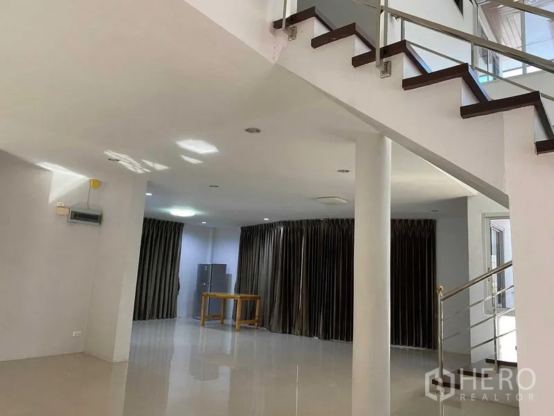 Home Office for rent in Khlong Toei, Bangkok - Bright open-plan living area with glossy tiles and staircase with glass railing.