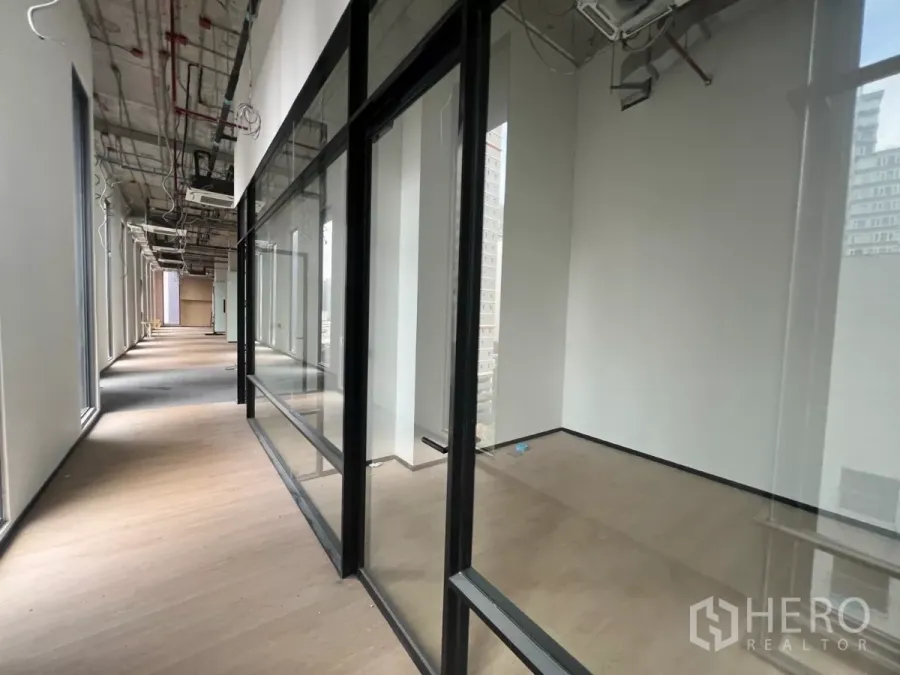 Retail Space for rent - Glass-front retail units along a wide corridor with wood floors and an exposed ceiling.