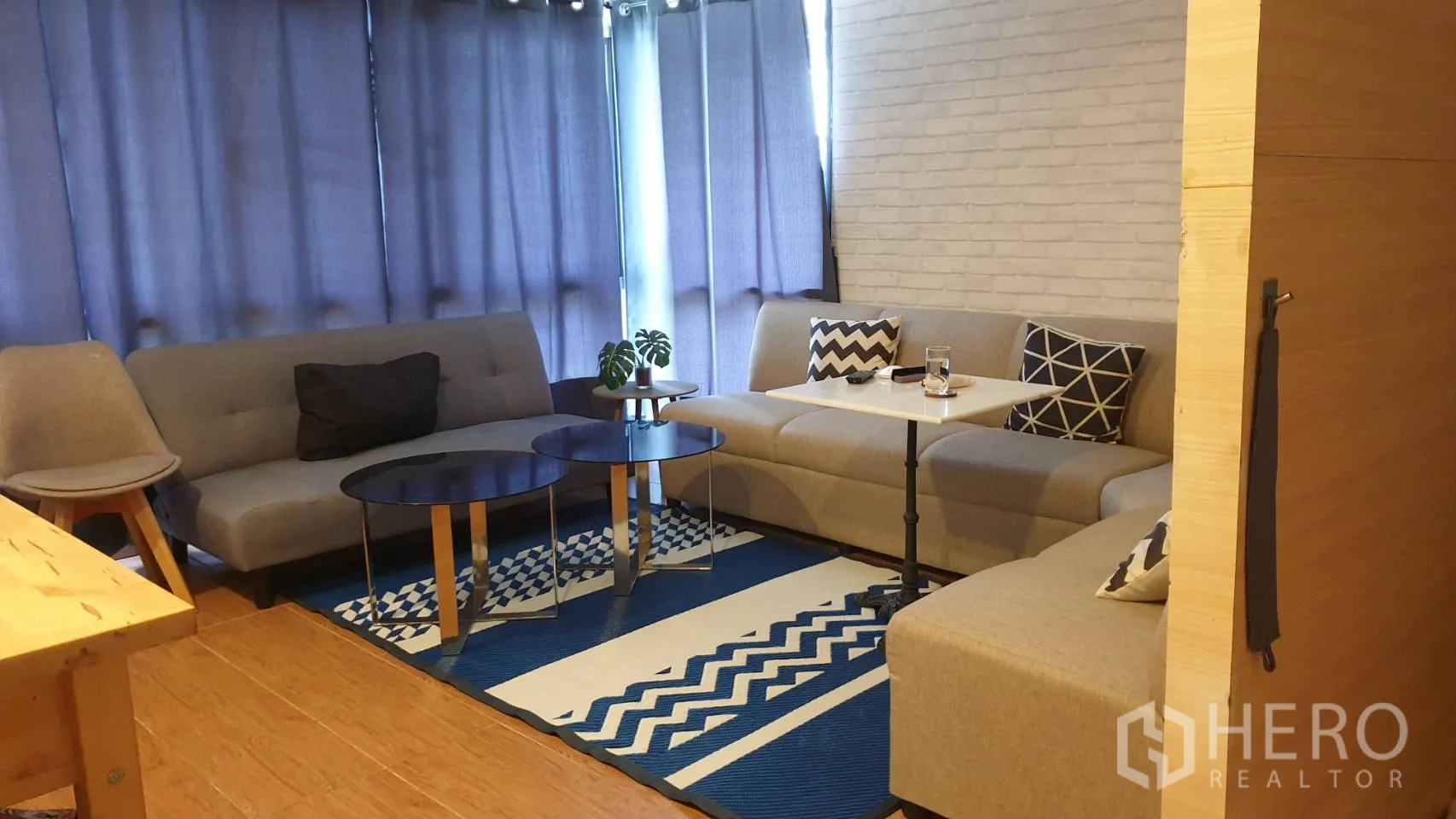 Detached House for rent in Watthana, Bangkok - Cozy lounge featuring gray sofas, round coffee tables, a patterned rug, and curtains.