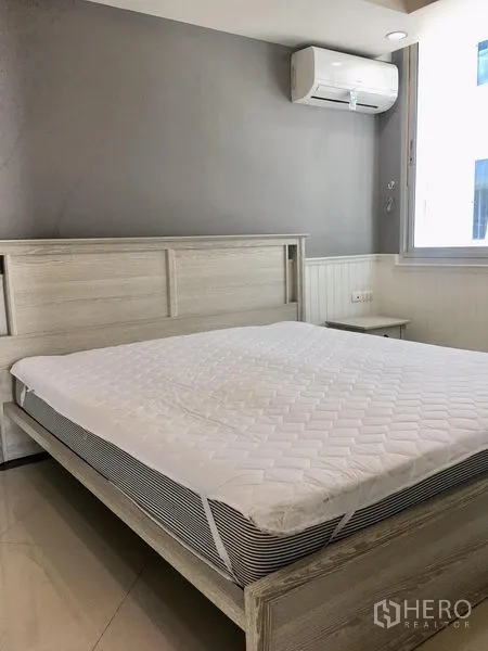 Condominium for rent in Khlong Toei, Bangkok - Second bedroom with air conditioner and gray feature wall.