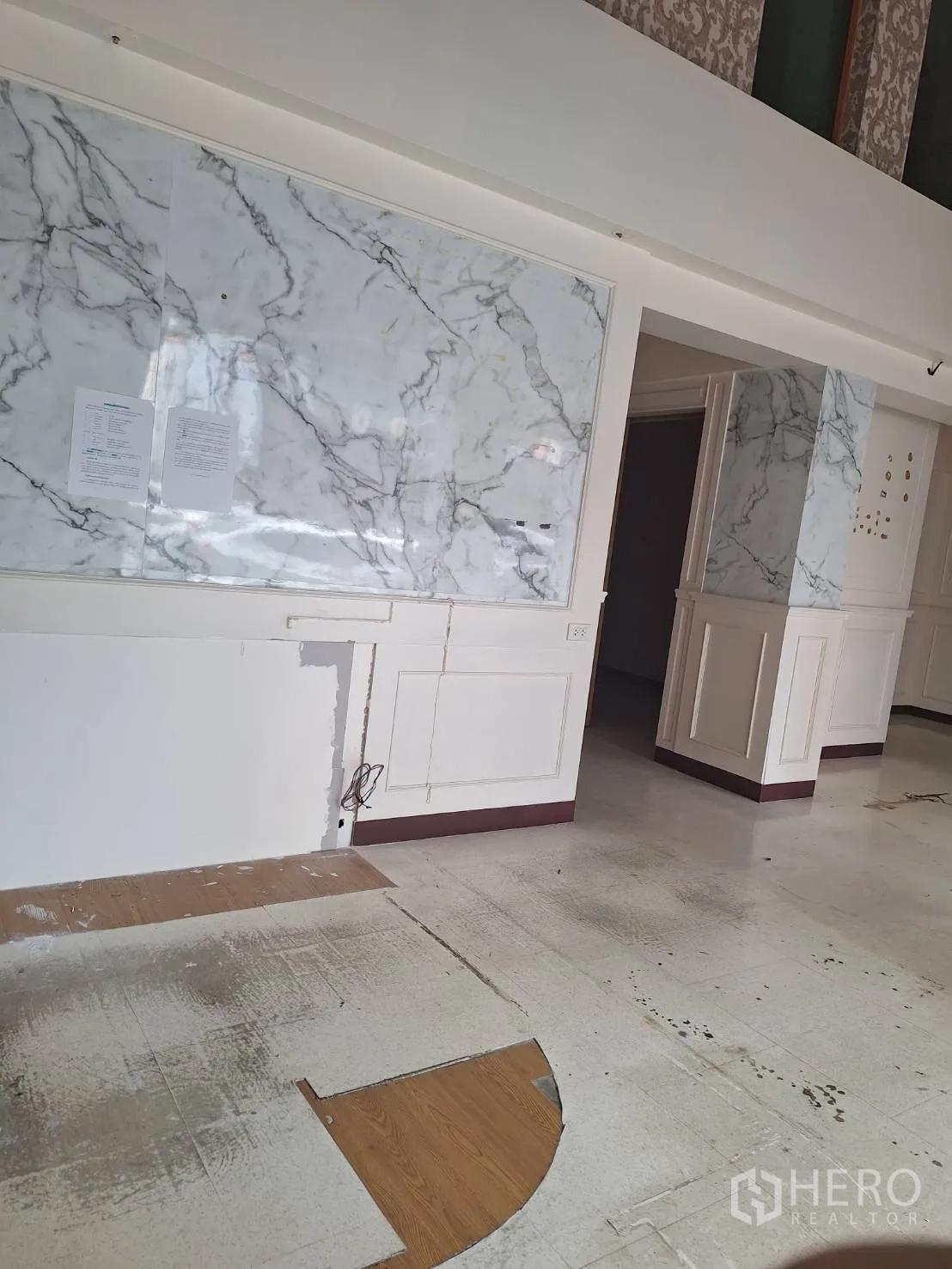 Retail Space for rent in Watthana, Bangkok - Front retail wall with large marble-look panels and floor section prepared for new flooring.