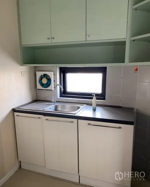 Office Space for rent in Din Daeng, Bangkok - Compact pantry with sink, black countertop, white base cabinets, green upper cupboards and a window.