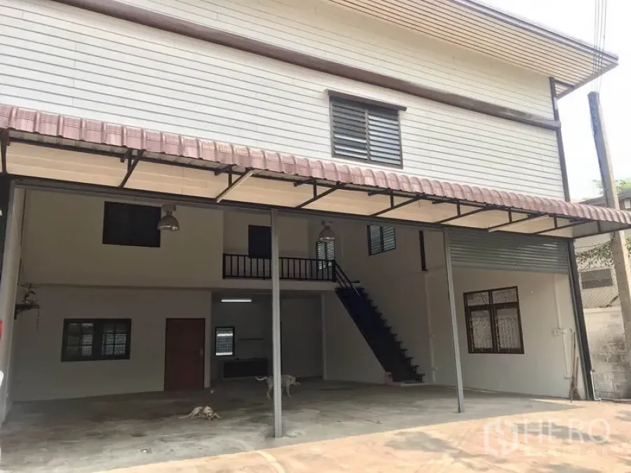 Warehouse for rent in Pathum Thani - Two-storey warehouse facade with wide covered loading bay and metal awning.