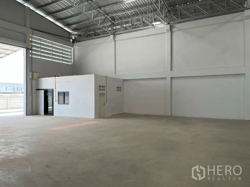 Warehouse for rent in Sam Phran, Nakhon Pathom - Interior view highlighting the built‑in office block, high walls, ventilation panels, and open loading space.