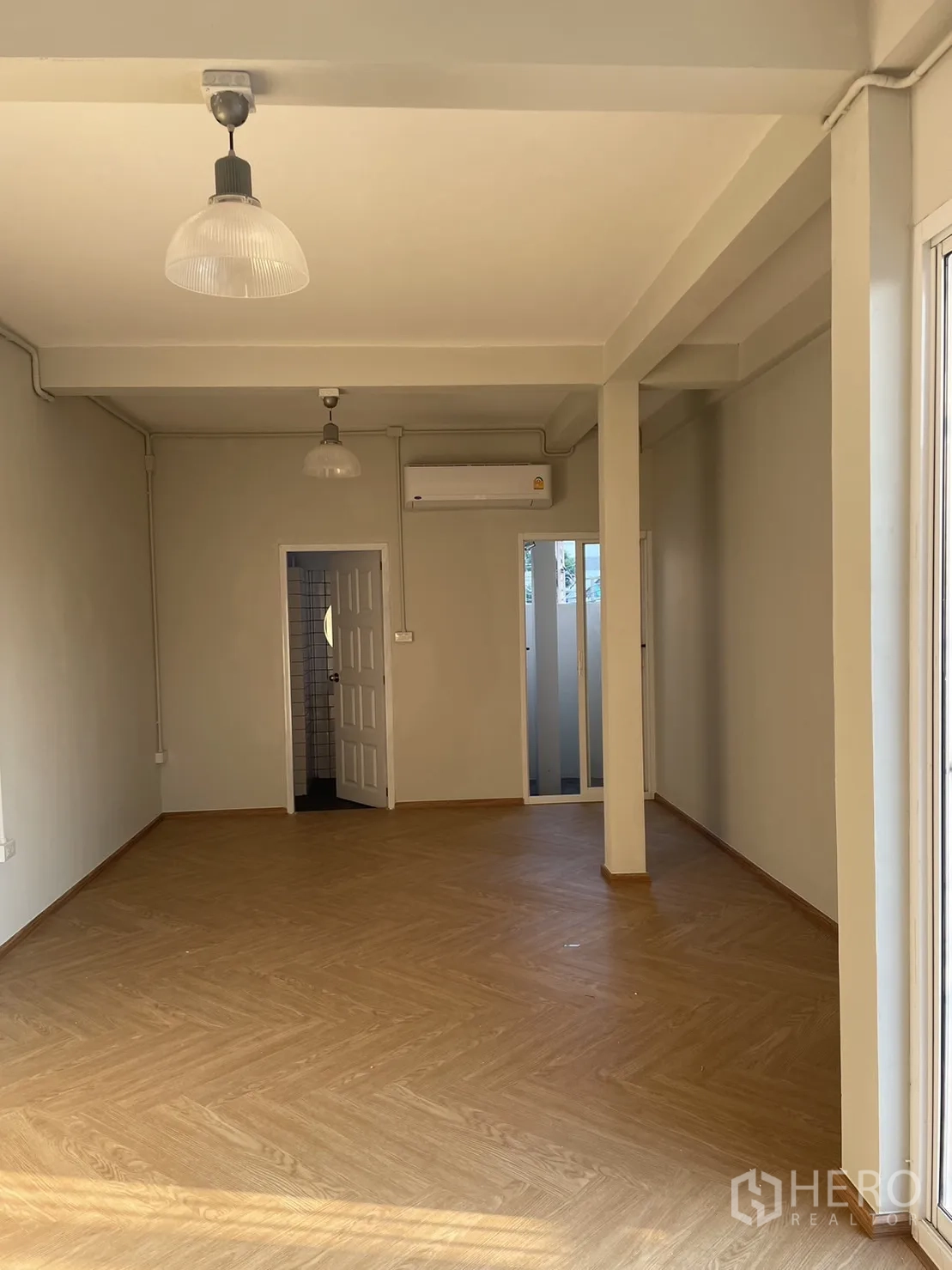 Detached House for rent or sale in Din Daeng, Bangkok - Large ground-floor room with air-con and doorway to bathroom, wood flooring.