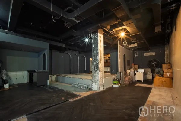 Retail Space for rent in Watthana, Bangkok - Spacious unit with exposed black ceiling, raised stage platform and storage boxes.