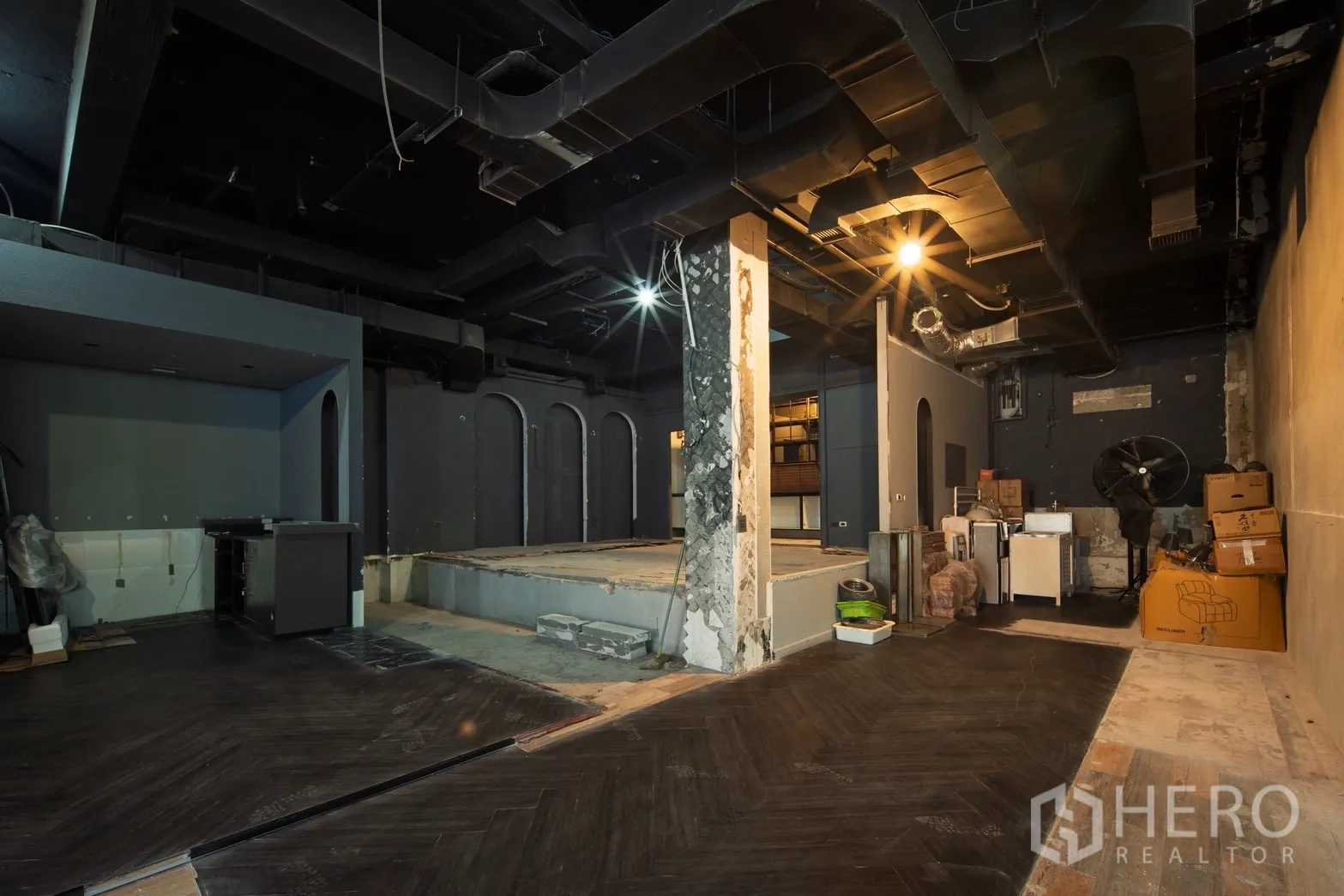 Retail Space for rent in Watthana, Bangkok - Spacious unit with exposed black ceiling, raised stage platform and storage boxes.