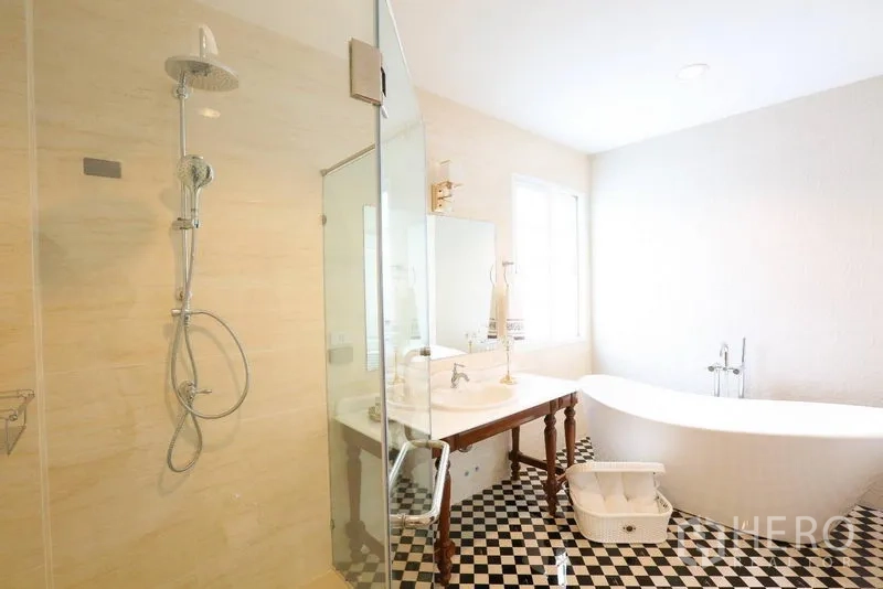 Detached House for rent in Bang Na, Bangkok - Bright bathroom with glass-enclosed shower, freestanding soaking tub and black-and-white tiled floor.
