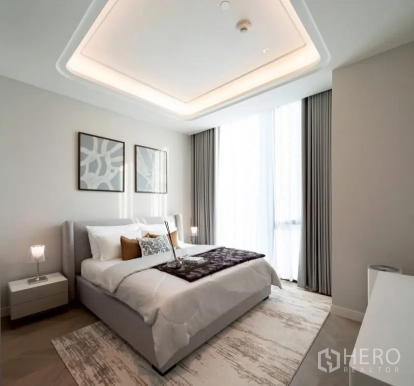 Condominium for rent or sale in Pathum Wan, Bangkok - Guest bedroom with soft neutral decor, framed art and natural light from tall windows.