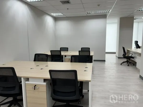 Office Space for rent in Sathon, Bangkok - Clustered desks with ergonomic chairs and a corridor leading to the reception area.