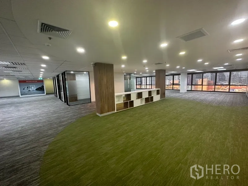办公空间 出租在Khlong Toei, Bangkok - 大型协作空间，绿色地毯、收纳柜与面向城市的窗景。