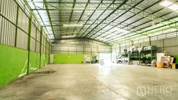Warehouse for rent in Thanyaburi, Pathum Thani - Spacious warehouse floor with a high-clearance steel truss roof, open storage area and rear loading door.