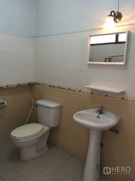 Townhouse for rent in Phra Khanong, Bangkok - Clean bathroom with toilet, pedestal sink, mirror and a wall sconce.