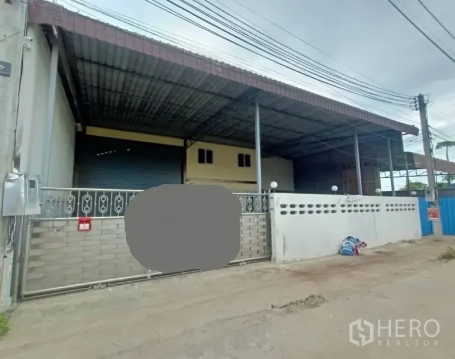 Factory for rent or sale in Mueang Samut Sakhon, Samut Sakhon - Street-front factory with secure sliding gate, high roof canopy and wide driveway.