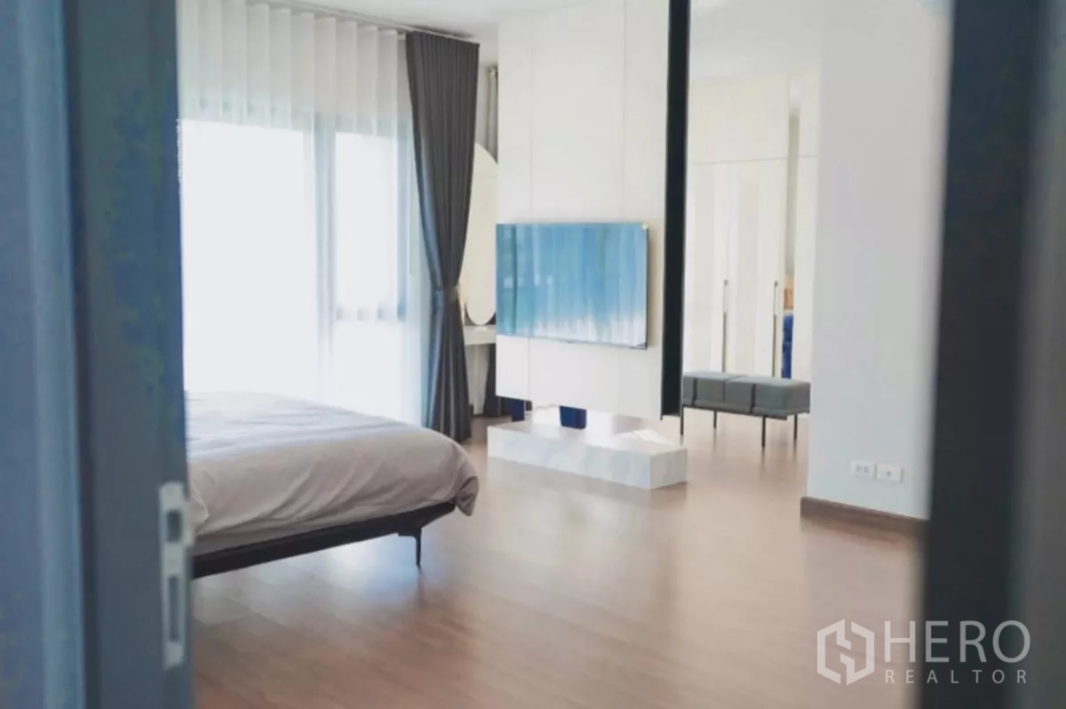 Detached House for rent in Bang Phli, Samut Prakan - Master suite overview with TV partition, seating area and wood floors.