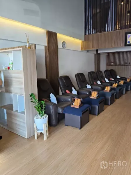 Shophouse for rent in Watthana, Bangkok - Row of leather recliner chairs with footstools along a wood floor massage area.