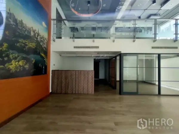 Office Space for rent in Pathum Wan, Bangkok - Open-plan office with high ceiling, ring light feature, mezzanine level, and floor-to-ceiling glass partitions.