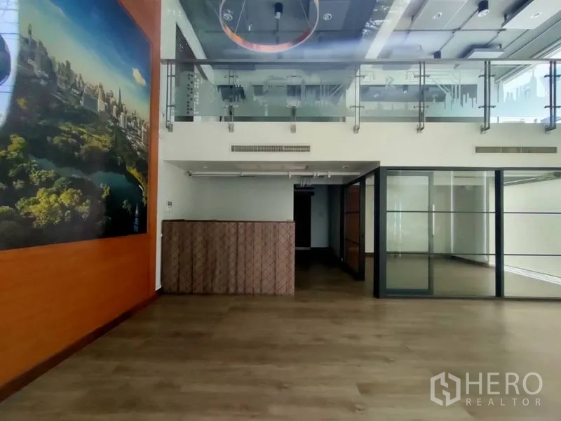 Office Space for rent in Pathum Wan, Bangkok - Open-plan office with high ceiling, ring light feature, mezzanine level, and floor-to-ceiling glass partitions.