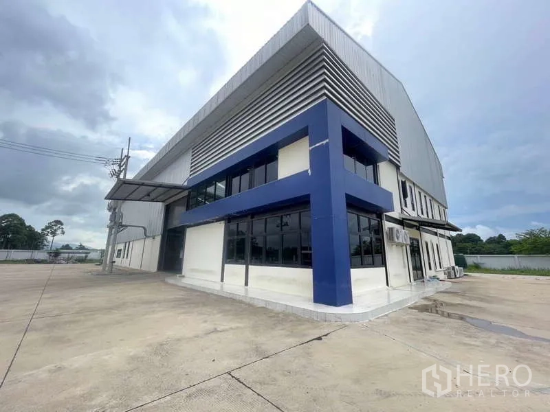Factory for sale in Si Racha, Chon Buri - Modern factory exterior with blue-and-white office block, wide concrete yard and loading canopy in Si Racha.