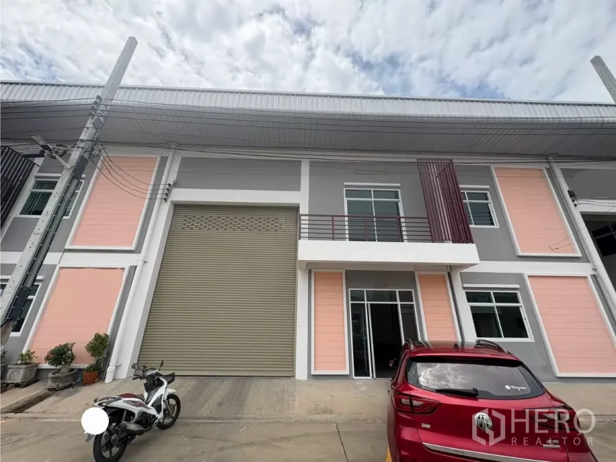 Factory for rent in Phra Samut Chedi, Samut Prakan - Modern factory facade with large roller shutter, mezzanine office windows and parking apron.