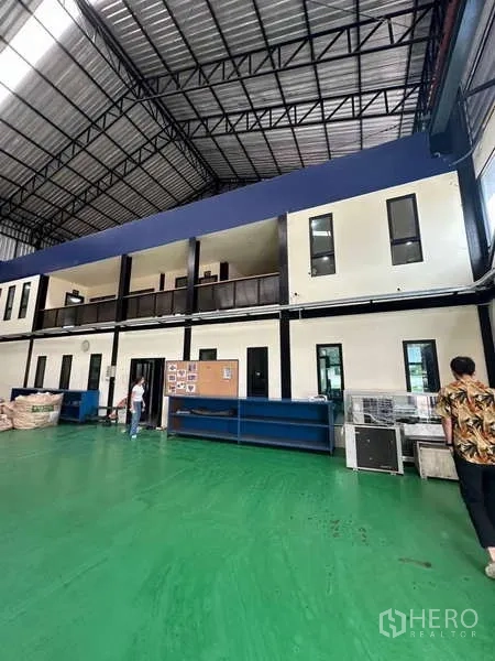 Factory for sale in Si Racha, Chon Buri - High-ceiling workshop interior with mezzanine offices and green epoxy floor.