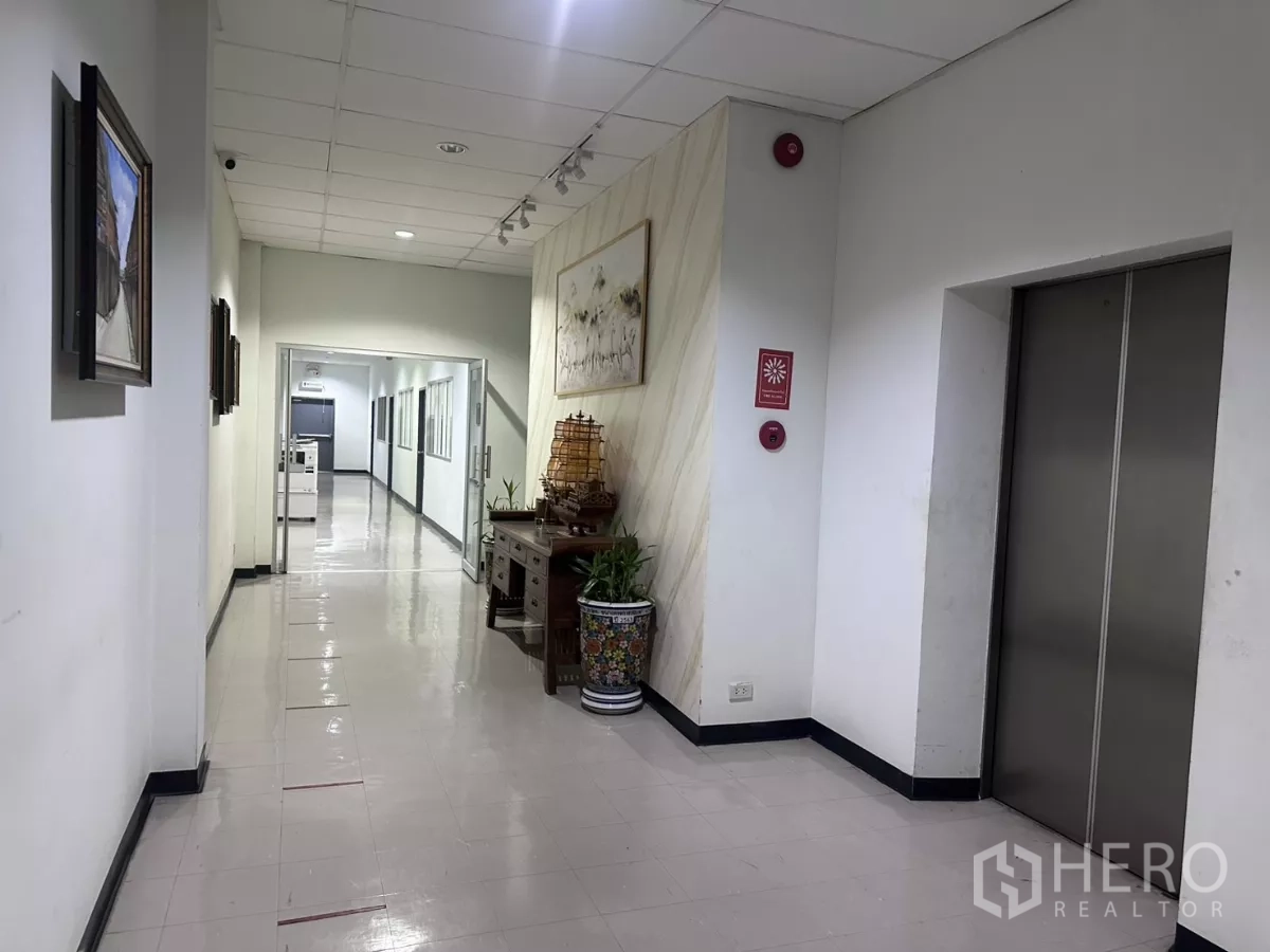 工厂 出售在Lat Krabang, Bangkok - 办公走廊，配电梯、装饰画与亮面地砖。