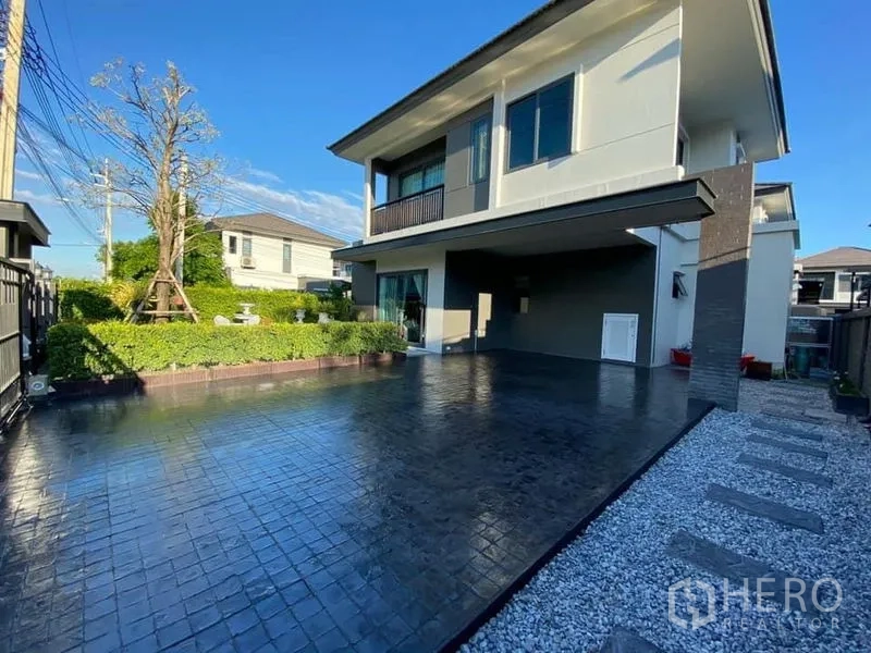Detached House for rent in Bang Phli, Samut Prakan - Modern two‑storey detached house in Bang Phli with a wide paved driveway, covered carport and landscaped front garden.