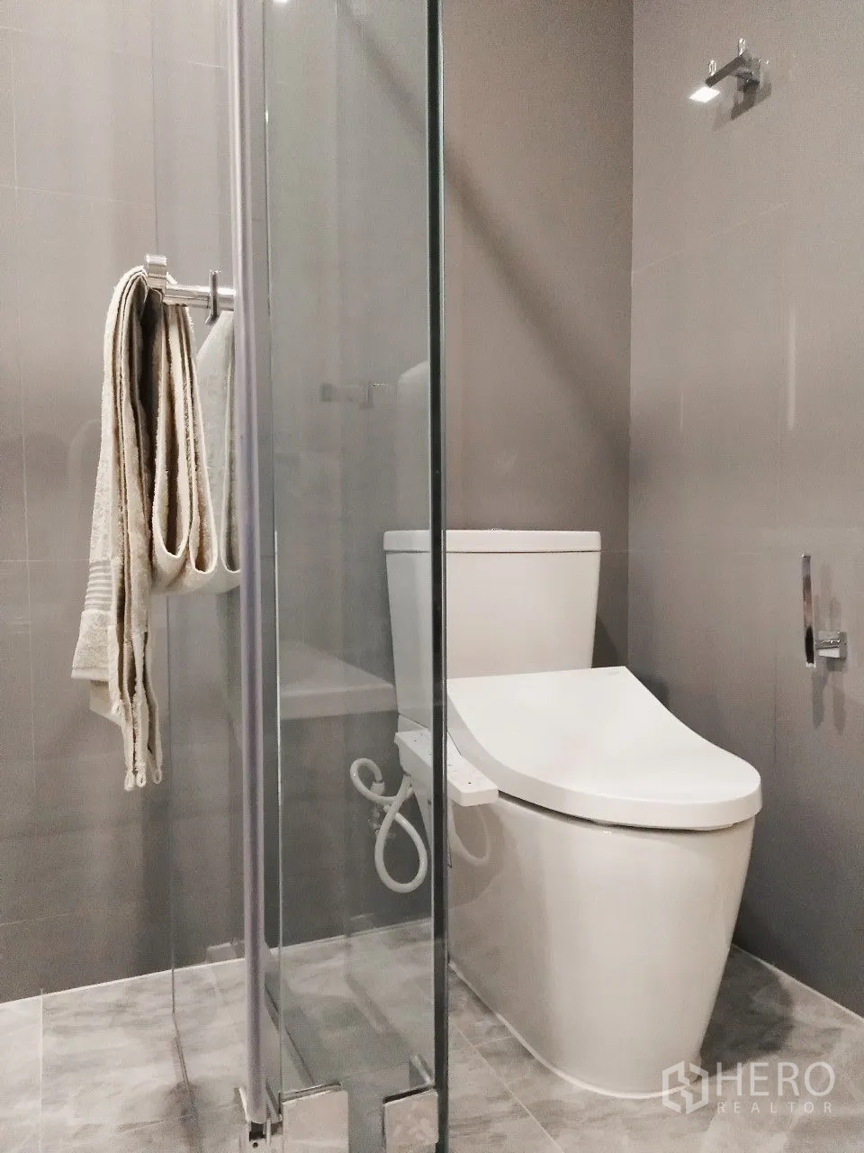 Condominium for rent in Watthana, Bangkok - Contemporary bathroom with toilet next to a clear glass shower enclosure.