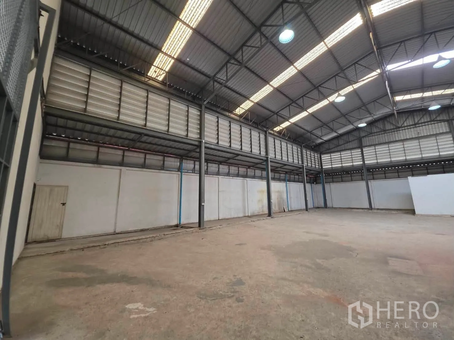 Warehouse for rent or sale in Phra Khanong, Bangkok - Spacious warehouse interior with high steel truss roof, skylights, and open concrete floor.