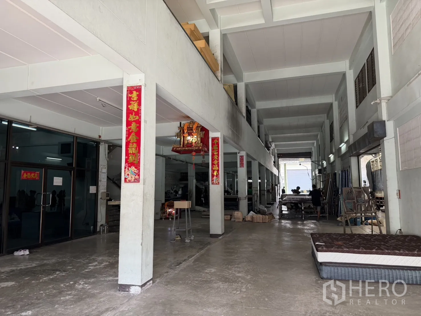 Factory for rent or sale in Bang Bon, Bangkok - Long covered corridor with glass doors and an indoor work area.