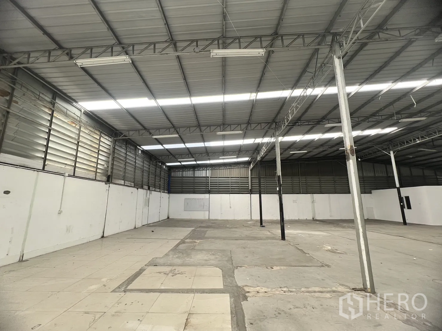 Warehouse for rent in Suan Luang, Bangkok - Wide warehouse bay featuring ventilated side walls and mixed concrete–tile flooring zones.