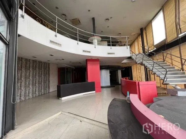 Retail Space for rent - Double-height lobby with feature staircase, curved reception counter and tall windows with blinds.