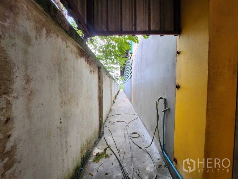 Warehouse for rent in Lat Krabang, Bangkok - Narrow side walkway with hose running between boundary walls.