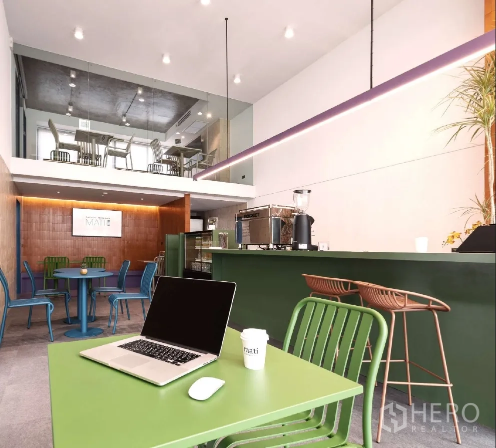 Home Office for rent or sale in Bang Khen, Bangkok - Open workspace with cafe-style counter, colorful tables, and mezzanine seating under track lights.
