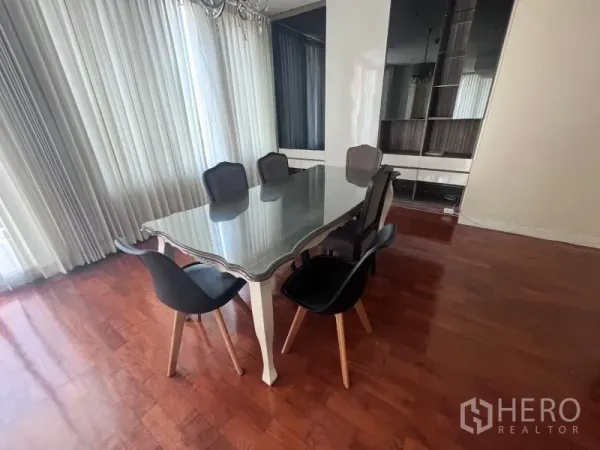 Condominium for rent in Khlong Toei, Bangkok - Sunlit dining area with a glass-top table for six, floor-to-ceiling curtains and hardwood floors in a Khlong Toei condo.