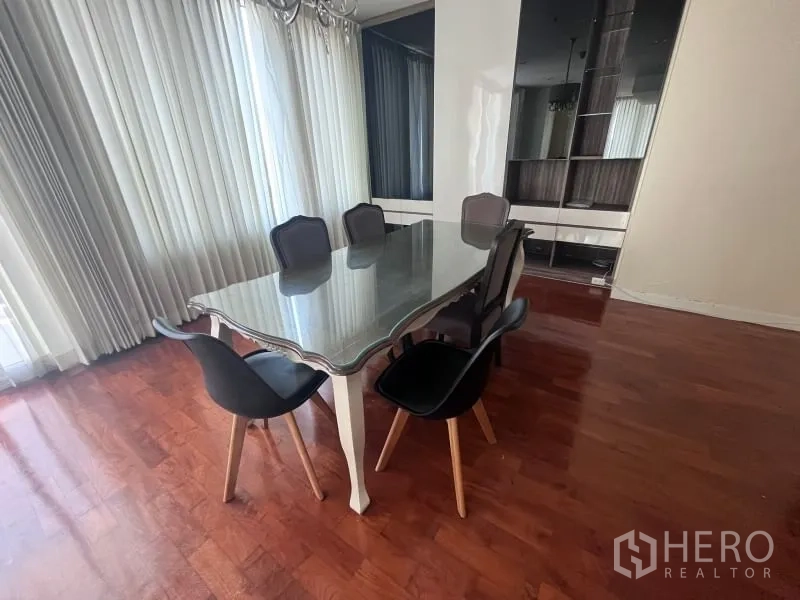 Condominium for rent in Khlong Toei, Bangkok - Sunlit dining area with a glass-top table for six, floor-to-ceiling curtains and hardwood floors in a Khlong Toei condo.
