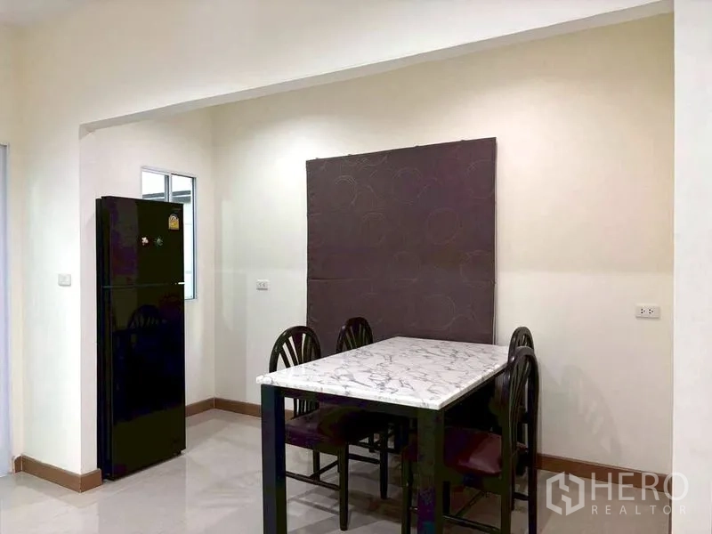 Townhouse for rent in Suan Luang, Bangkok - Dining area with marble-top table, chairs, and refrigerator.