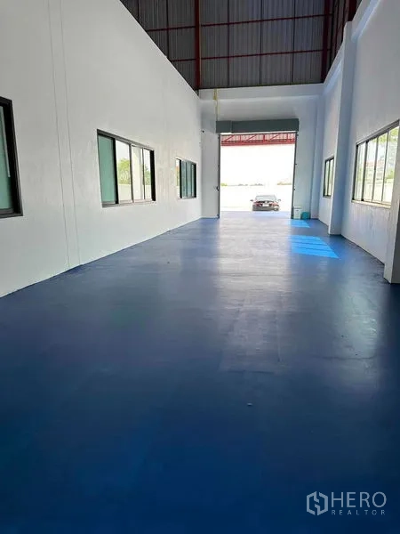 Warehouse for sale in Khlong Luang, Pathum Thani - Long warehouse bay with windows leading to a roller door and driveway.