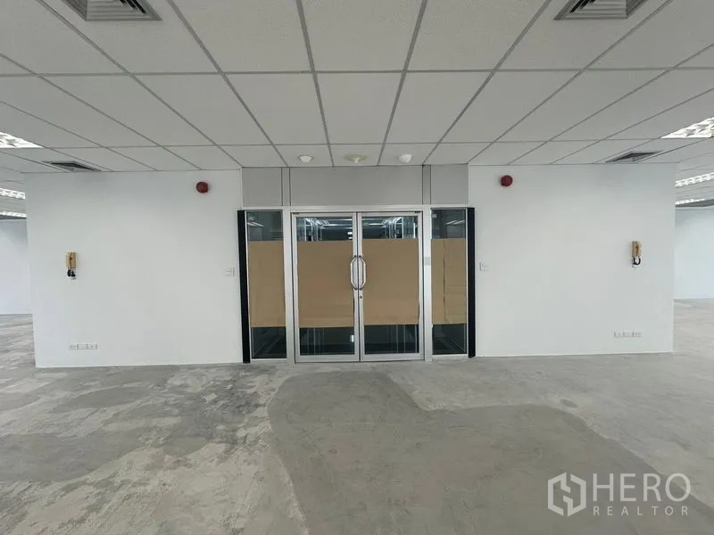 Office Space for rent in Bang Rak, Bangkok - Unfurnished open-plan office with suspended ceiling, glass double doors and emergency fixtures.