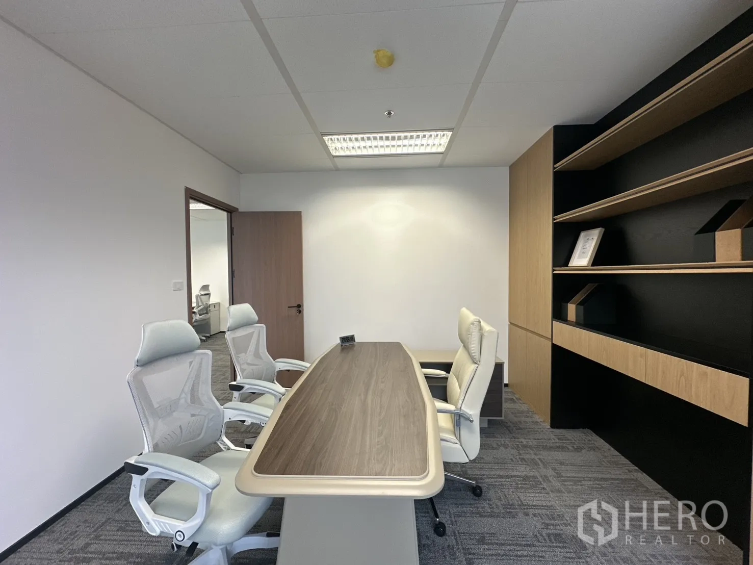 Office Space for rent in Pathum Wan, Bangkok - Private meeting room with wood table, white mesh chairs, and built-in shelves.