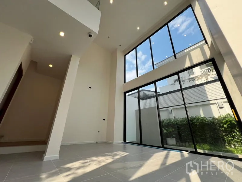 Home Office for sale in Phra Khanong, Bangkok - Sunlit double‑height lounge with full‑height windows overlooking the garden.