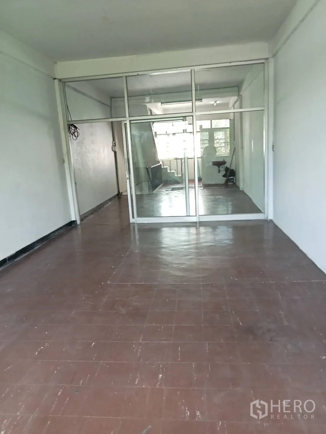 店屋 出租在Phra Khanong, Bangkok - 楼上房间，棕色地砖，整面玻璃隔断并连接楼梯区域。