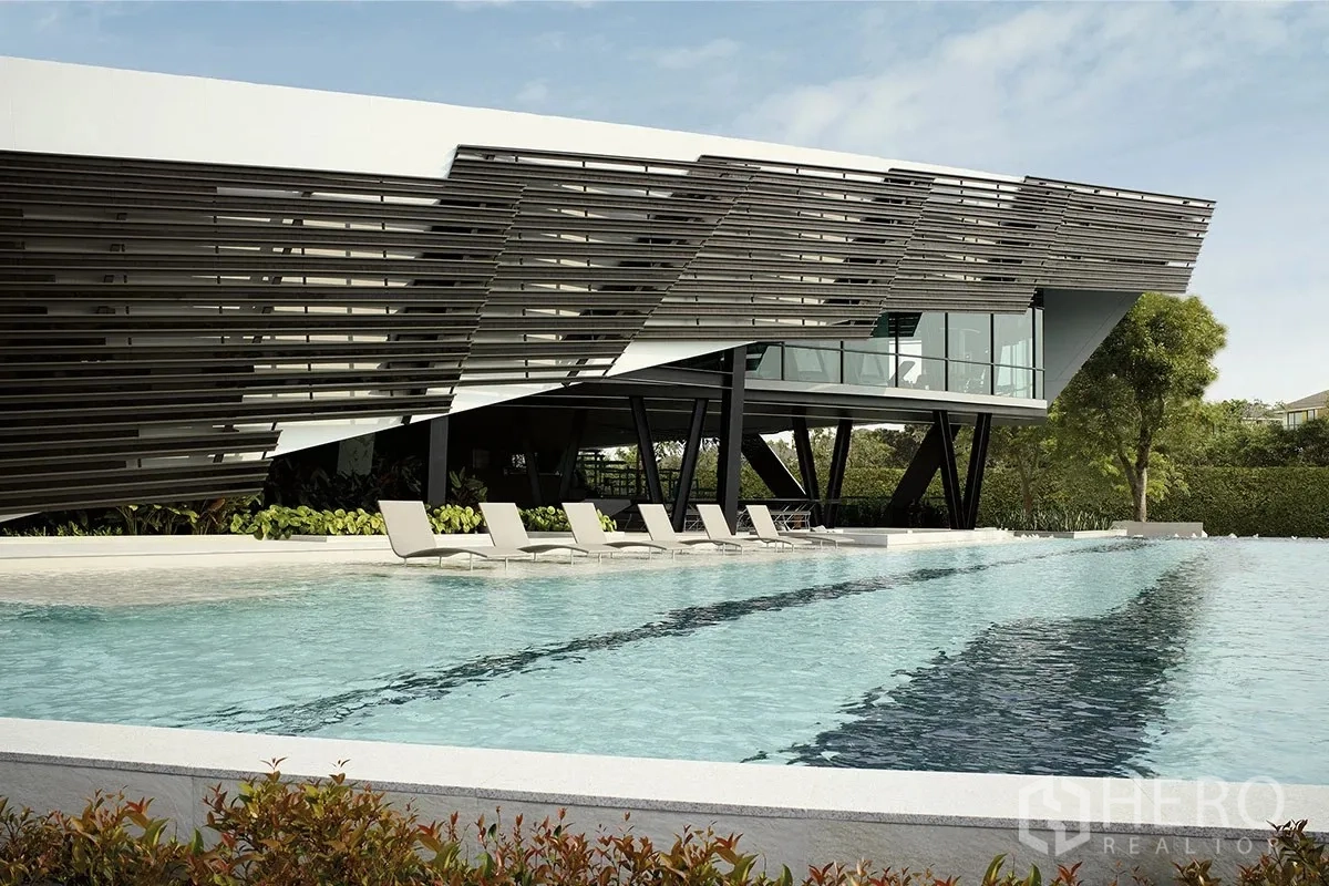 Detached House for rent or sale in Pathum Thani - Lap pool and clubhouse building with sun loungers and greenery.